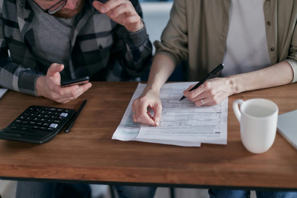 A couple collaboratively managing finances with papers and calculator in hand.